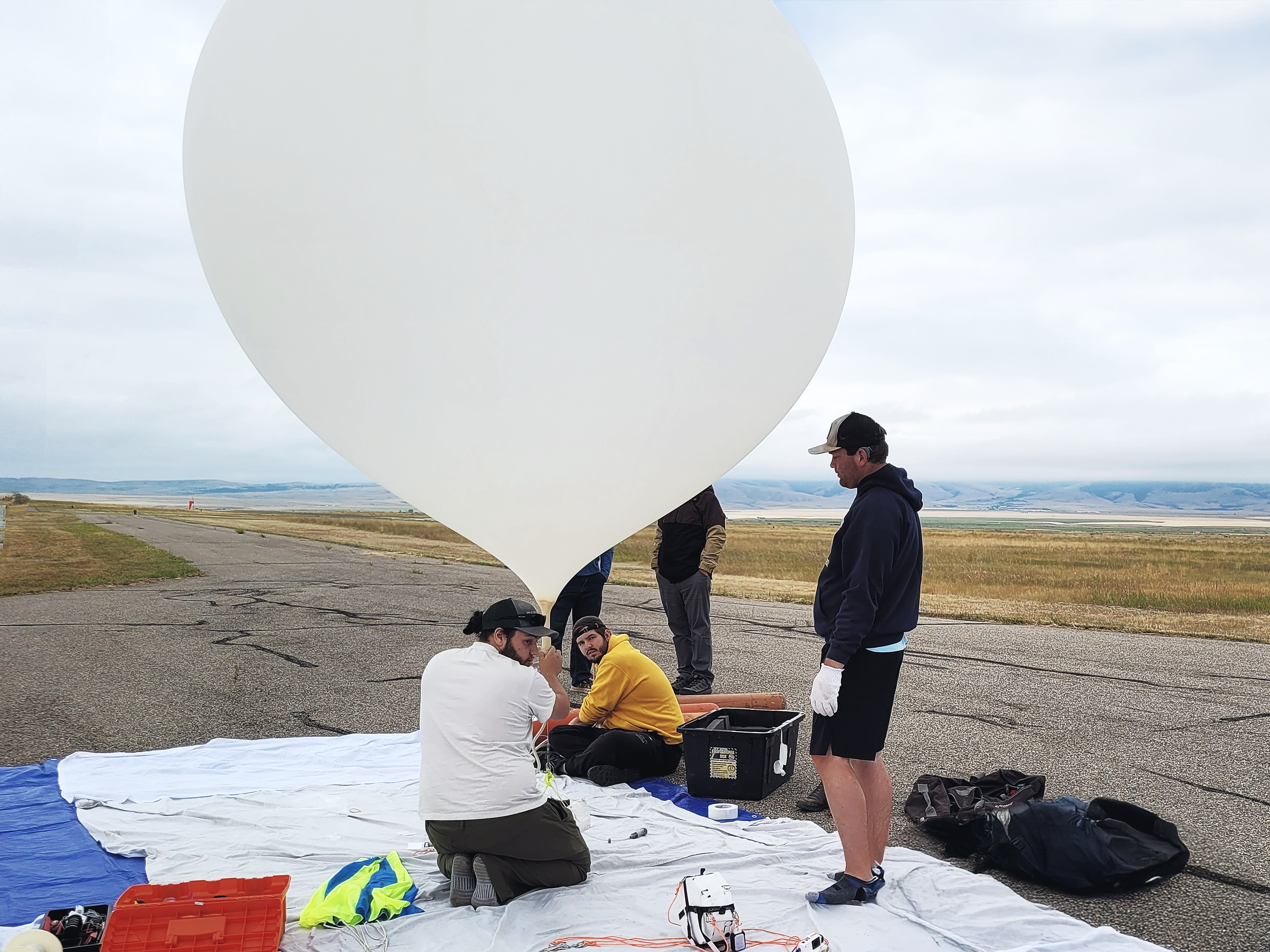 People surrounding a balloon as it is filled.