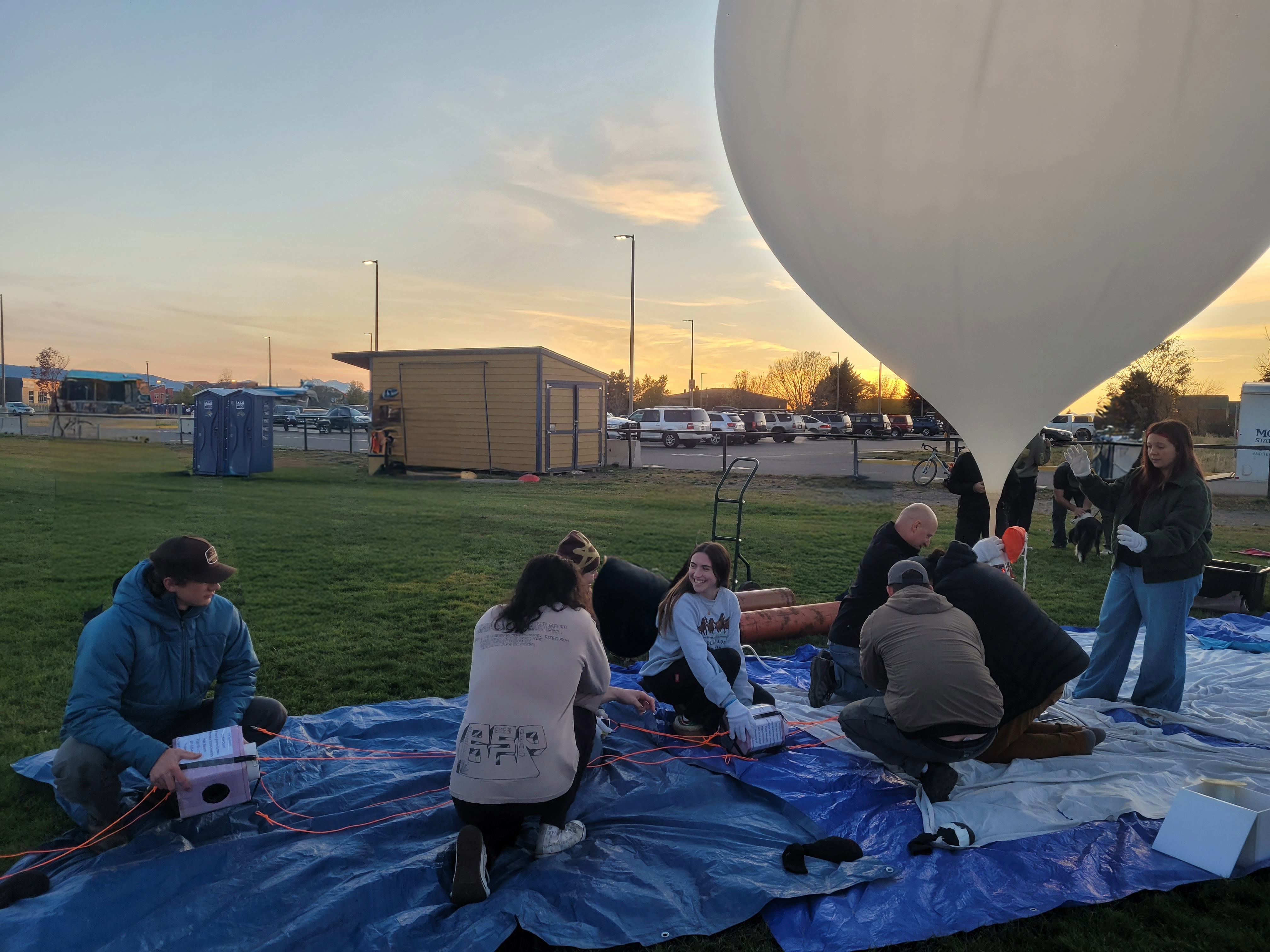 People crowding around the balloon inflaiting and the payloads.